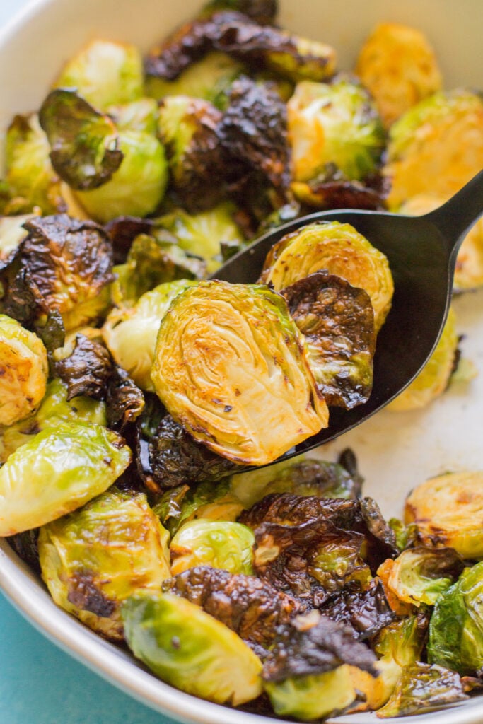 A close up of a spoon scooping up buffalo brussels sprouts