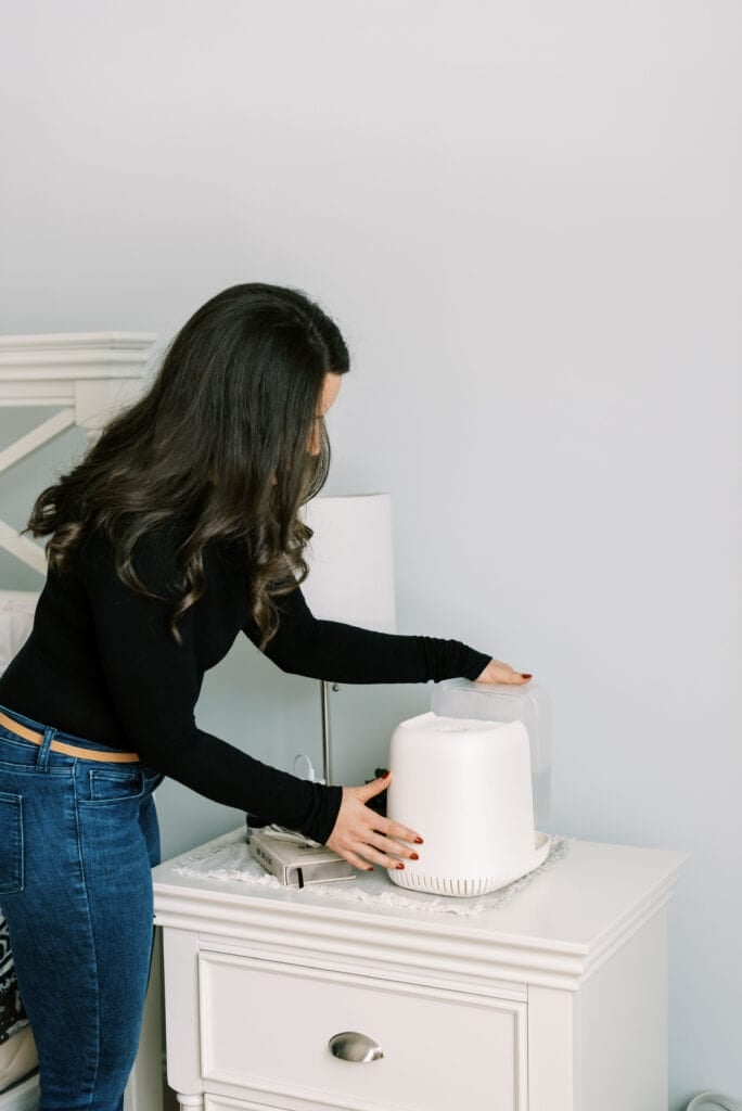 A girl refilling the canopy humidifier on a nighstand