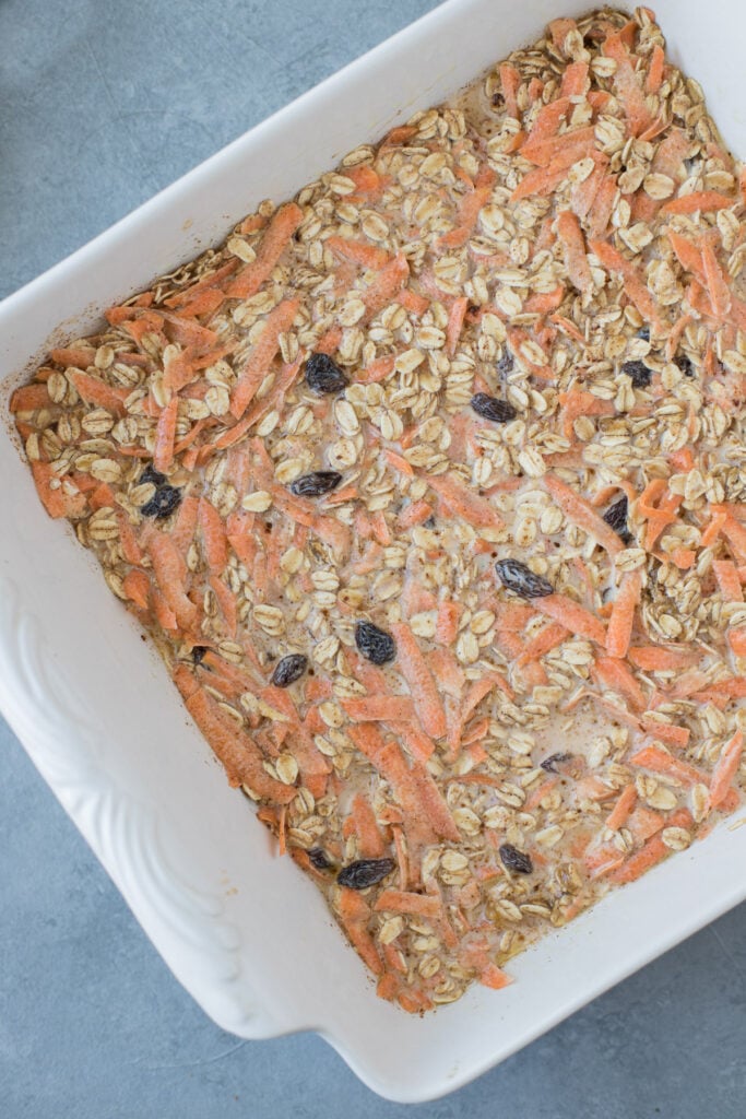 A white 8x8 baking dish filled with carrot cake oats before they are baked