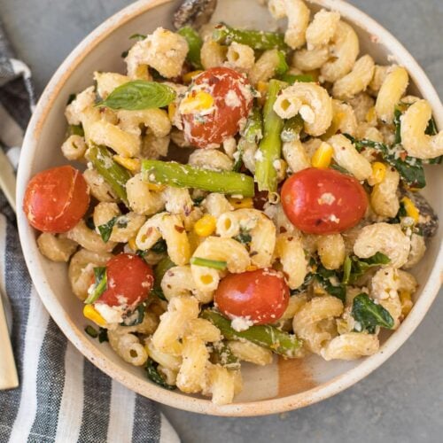 A close up of a bowl of baked feta pasta on a grey background
