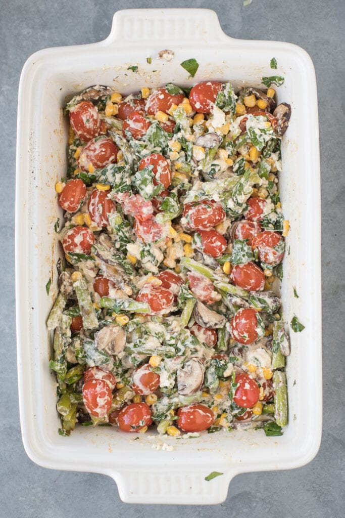 vegetables and feta being stirred together for a creamy baked feta pasta