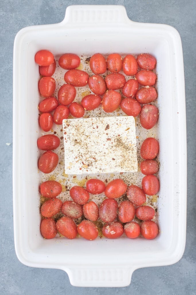 A white baking dish with tomatoes and feta in the middle.