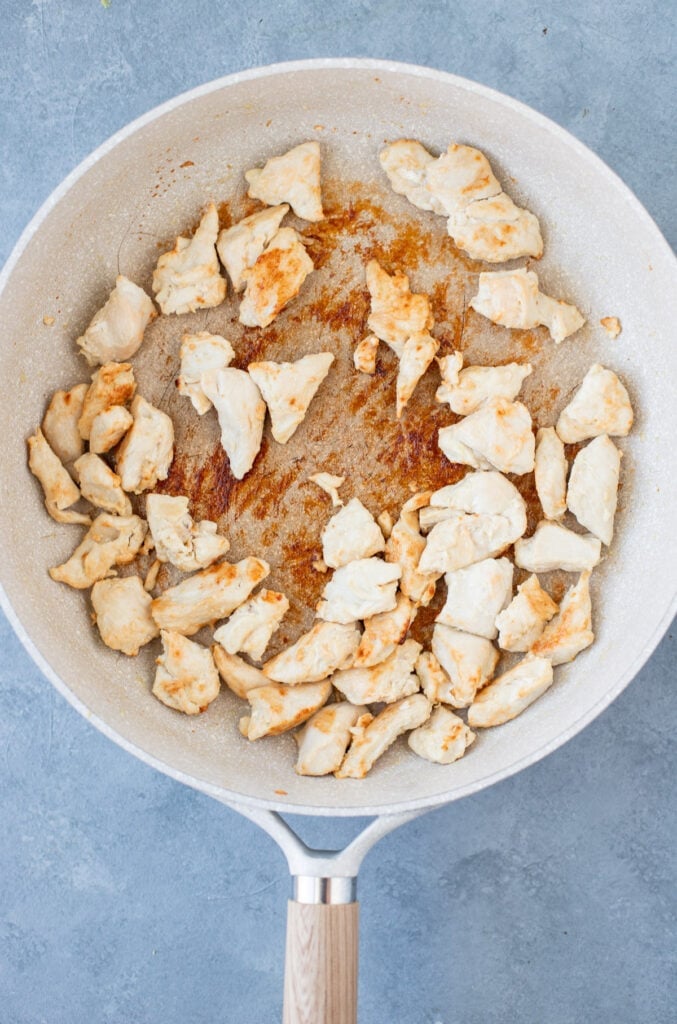 Chicken in a white pan browning for a healthy stir fry