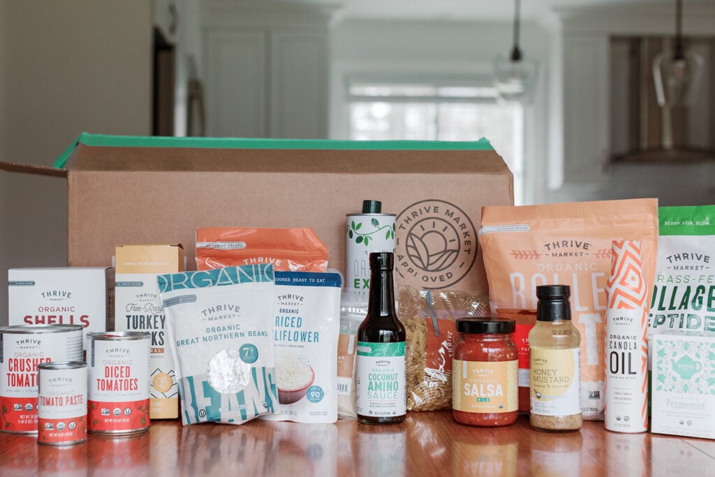 Pantry Staples spread out on a kitchen table - canned goods, dry goods, olive oil, salsas and more