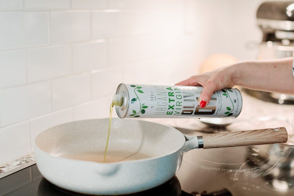 Olive oil being poured into a pan - a post about healthy pantry staples