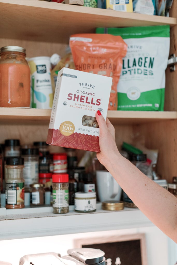 A close up of a hand reaching into a pantry to grab a box of pasta