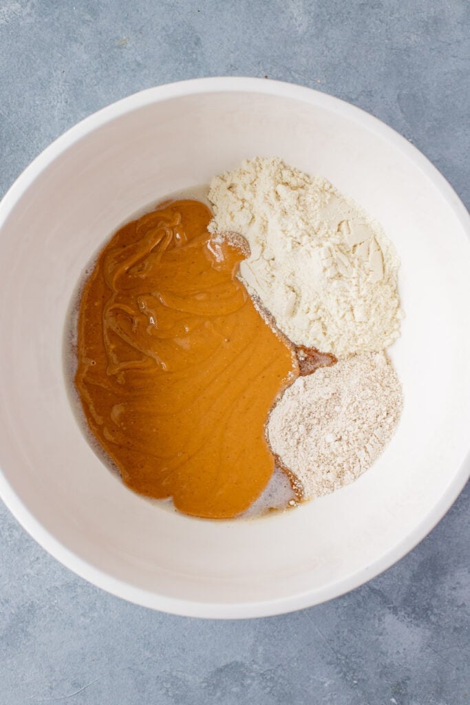 Ingredients for Peanut Butter Protein Bars in a large white bowl before being mixed together