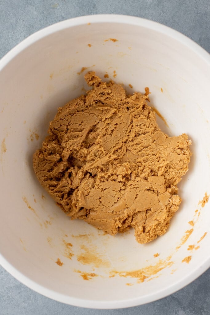 Ingredients for Peanut Butter Protein Bars in a large white bowl after being mixed together. The dough resembles cookie dough