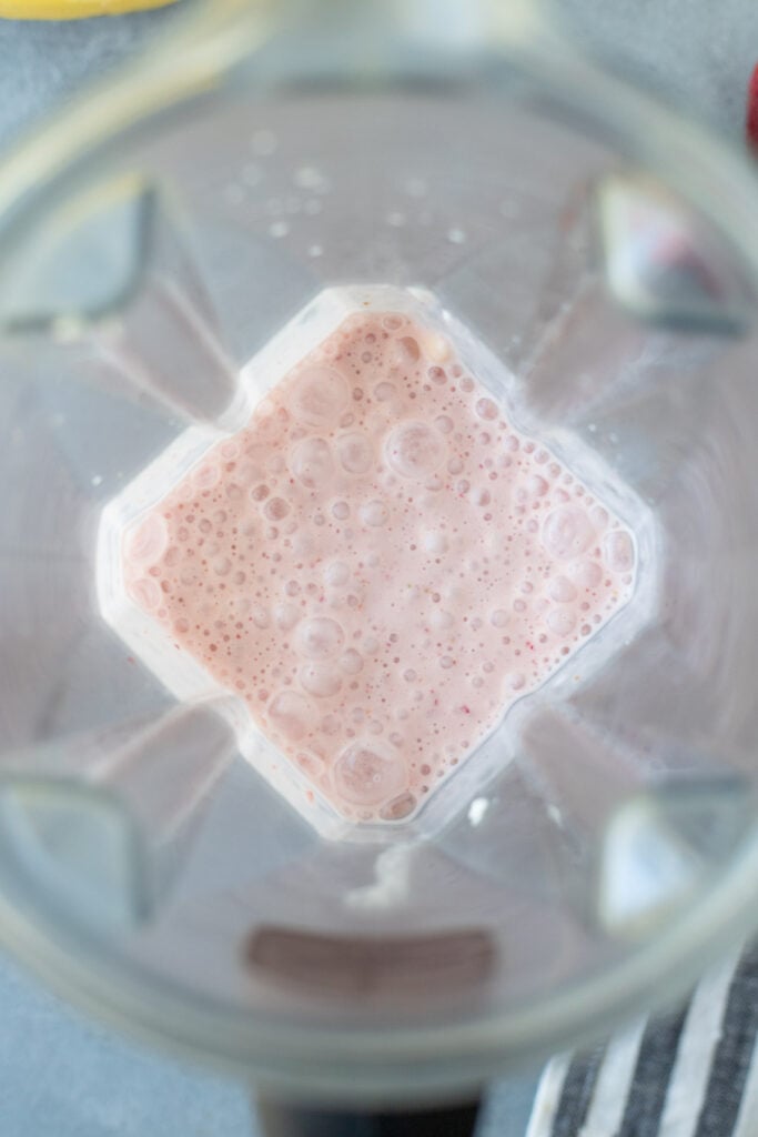 A close up of a healthy strawberry banana smoothie in a blender after being blended