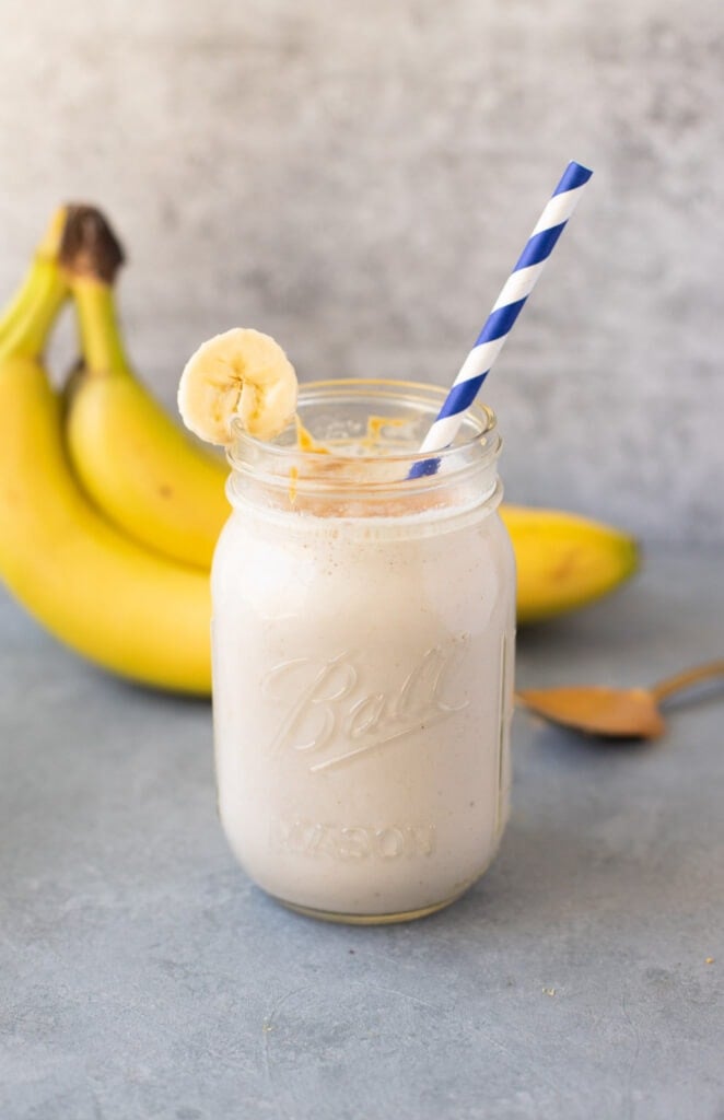 A close up of a banana smoothie in a mason jar on a grey background