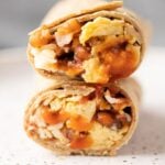 A close up of the best healthy breakfast burritos cut in half and stacked on top of one another.