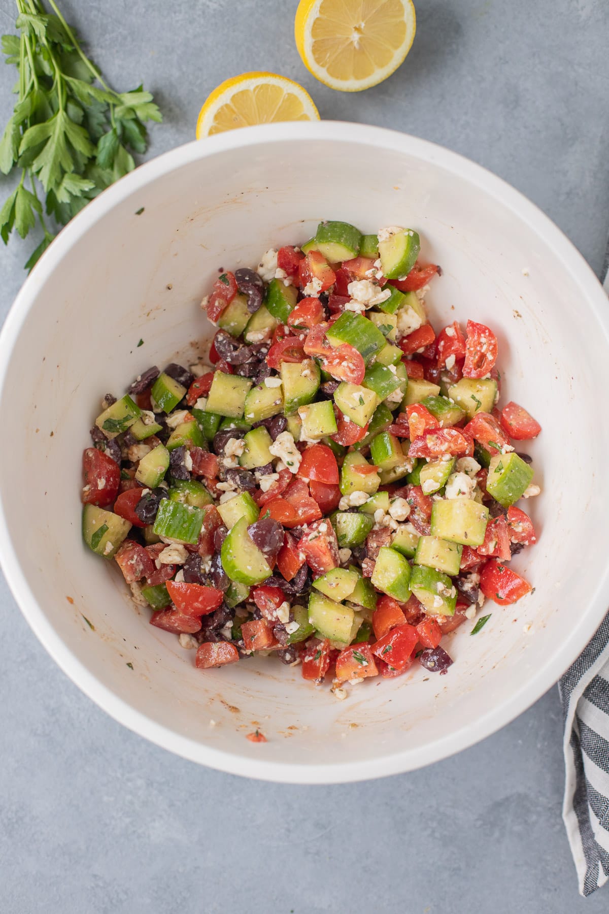 The Best Greek Salad in a white bowl mixed together on a grey background