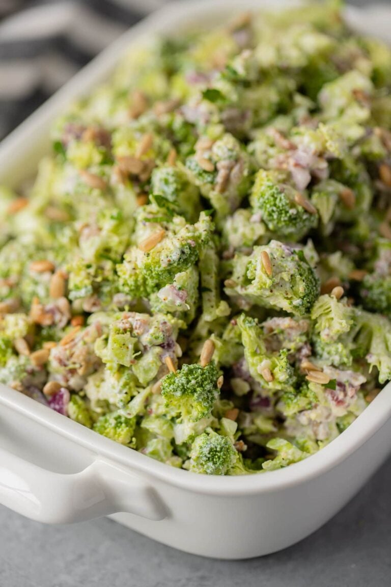 a white bowl of healthy broccoli salad on a grey background