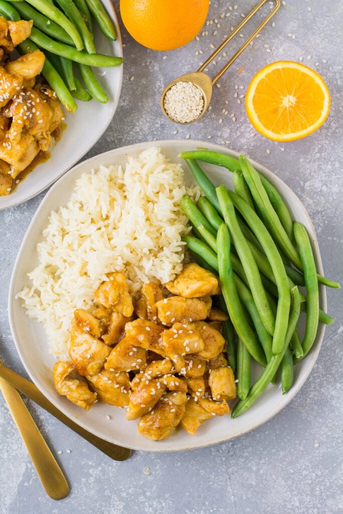 An overhead image of healthy chicken recipes on a white plate with green beans and rice