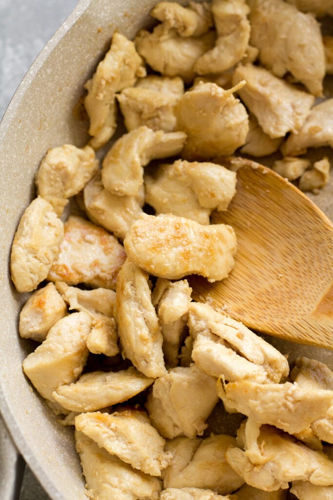a wooden spoon removing cooked orange chicken out of hte pot for healthy orange chicken