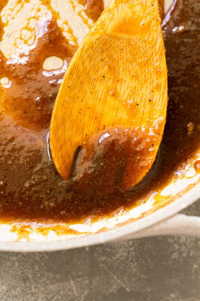 a spoon holding up thickened orange chicken sauce