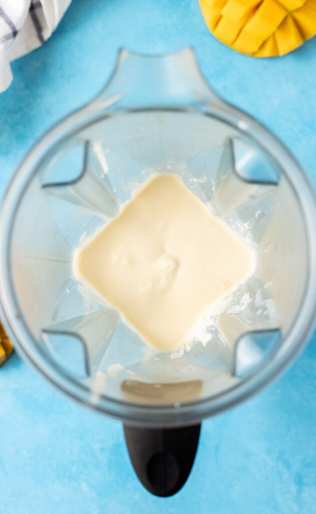ingredients for a frozen mango smoothie blended together showing How To Make a Mango Smoothie