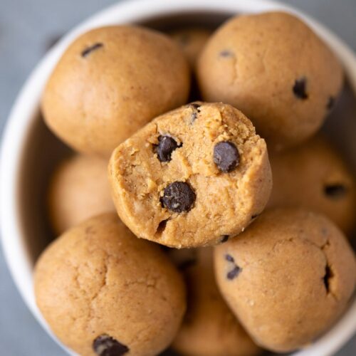 A close up of No Bake Protein Balls Recipe in a small white bowl with a bite being taken out of it