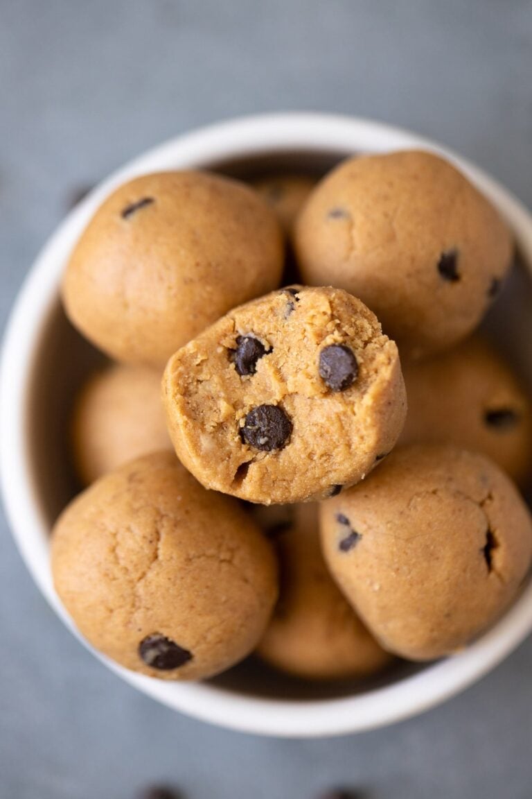 A close up of No Bake Protein Balls Recipe in a small white bowl with a bite being taken out of it