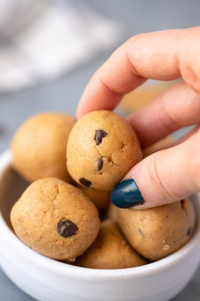A hand taking a protein all from a bowl of energy bites