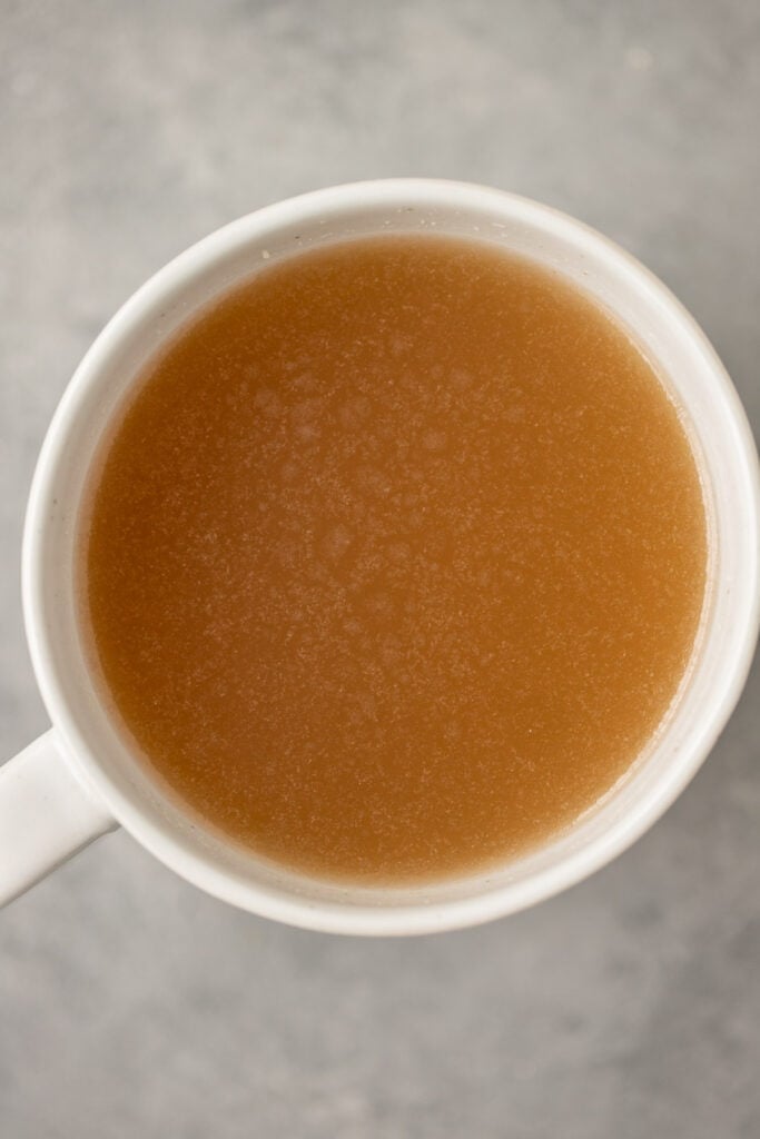 A mug filled with beef bone broth on a grey background