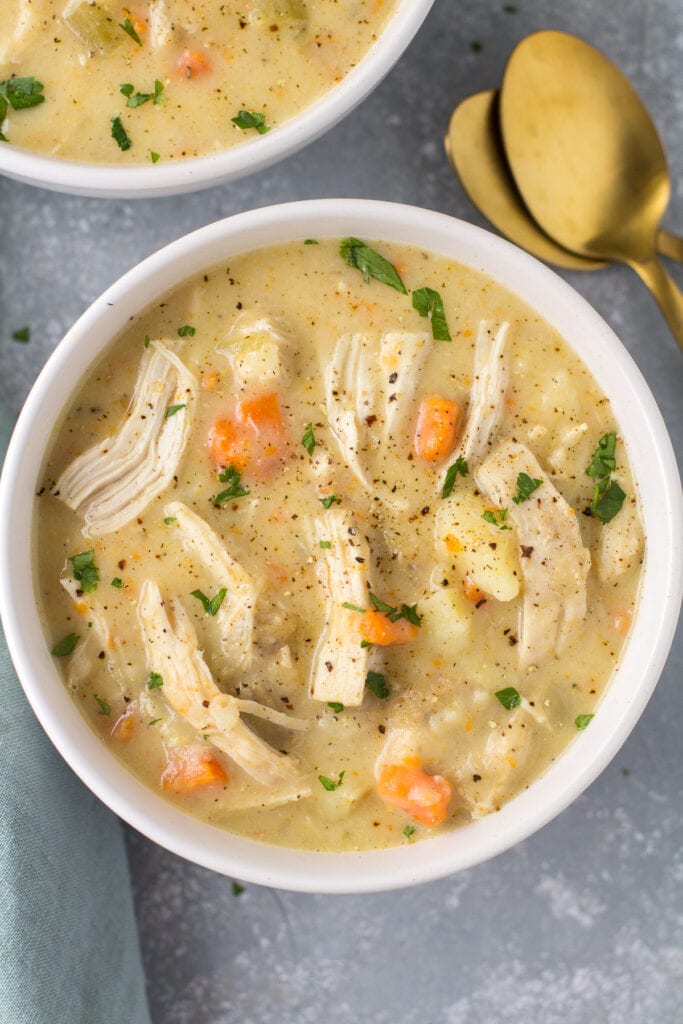 A bowl of chicken pot pie soup with spoons off to the side