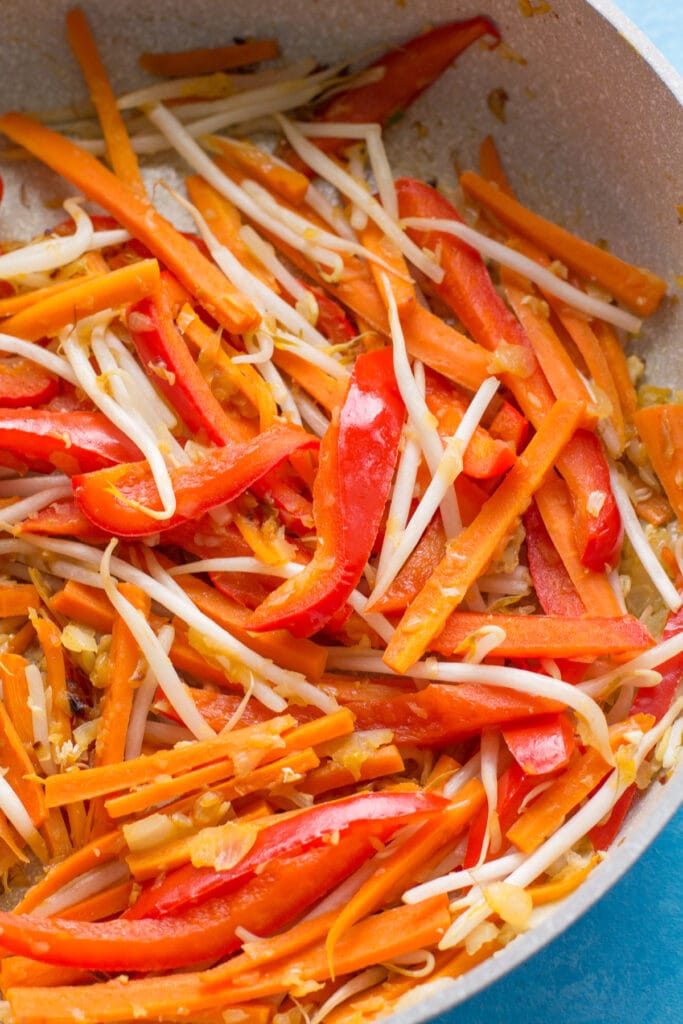 Vegetables for healthy pad thai being sautéd together in a white pan