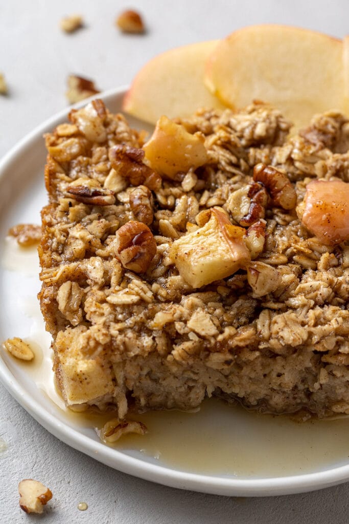 Baked oatmeal fresh out of the oven on a white plate on a grey background