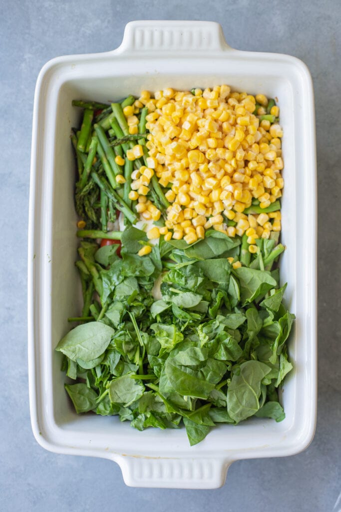 Corn and spinach being added to goat cheese pasta