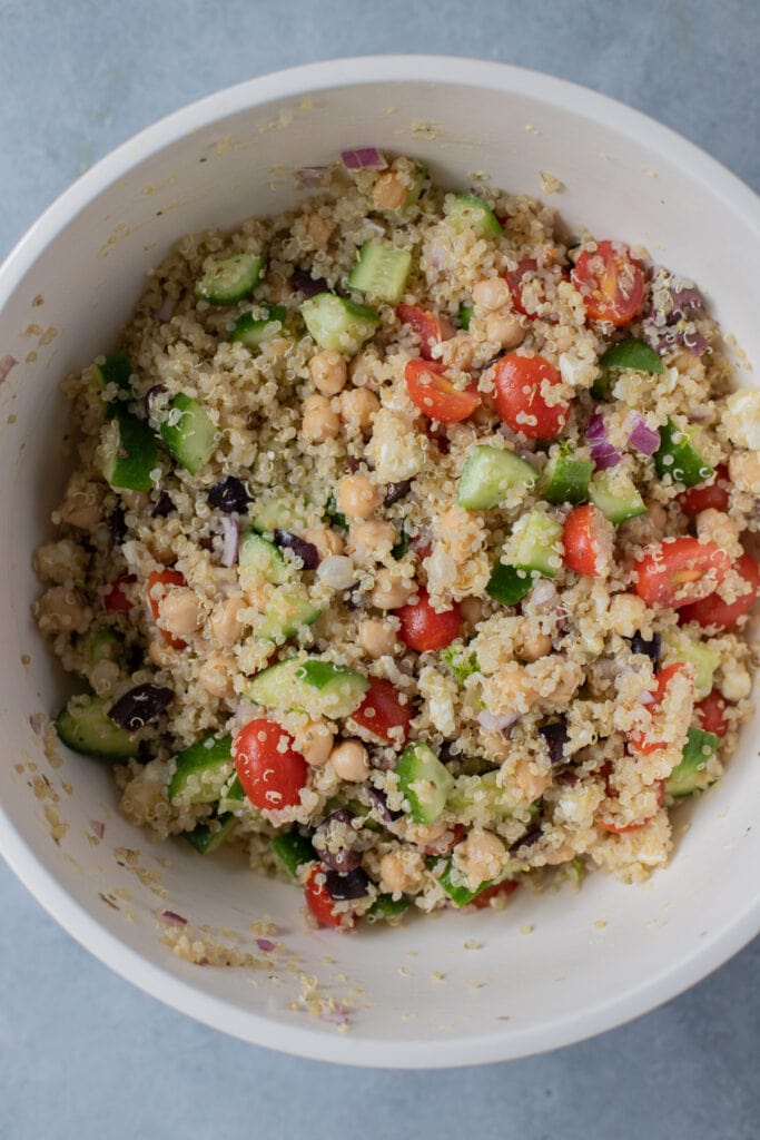 Greek Quinoa Salad in a white bowl after being mixed together