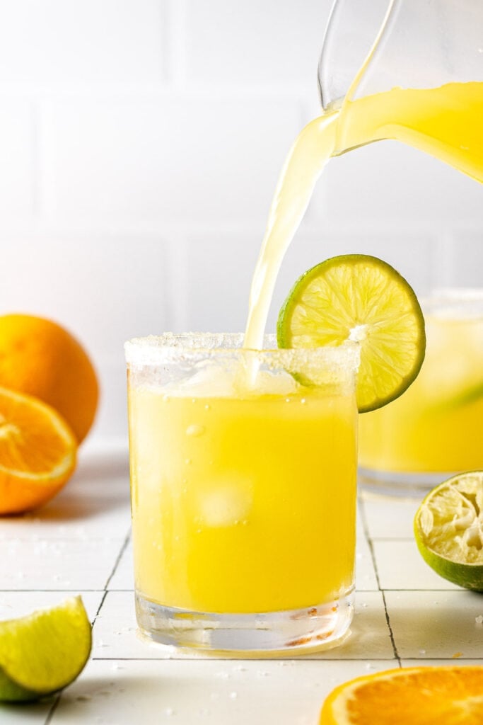 A pitcher pouring a glass of skinny spicy margarita