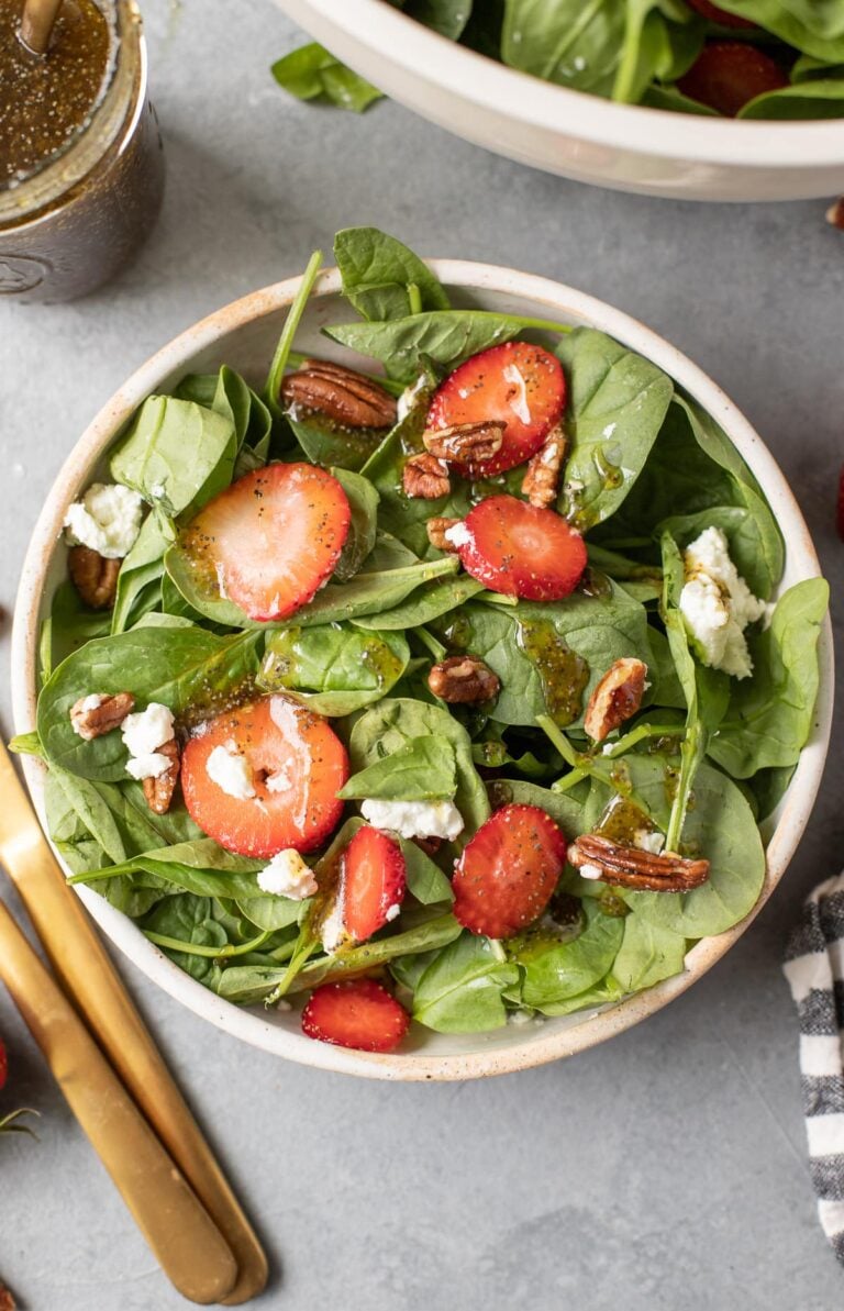 Strawberry Spinach Salad in a white bowl on a grey background