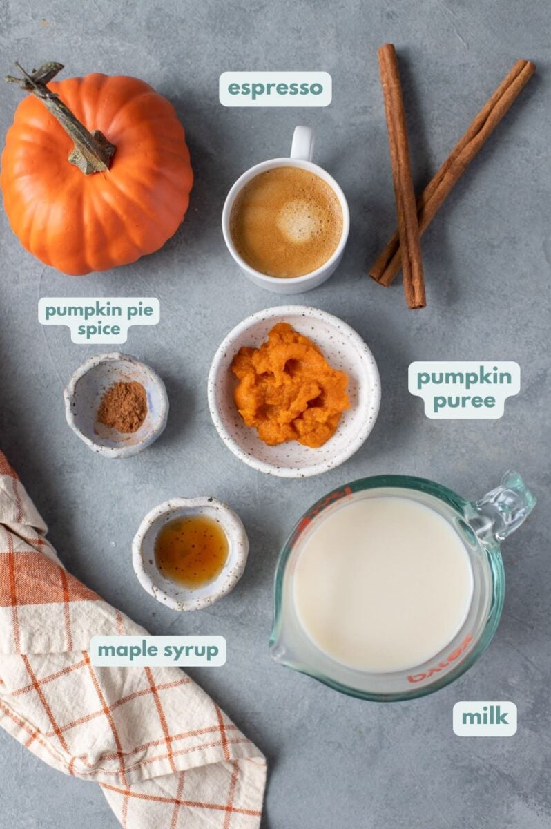 Healthy Pumpkin Spice Latte ingredients. espresso, a jar of milk, maple syrup, cinnamon, pumpkin.