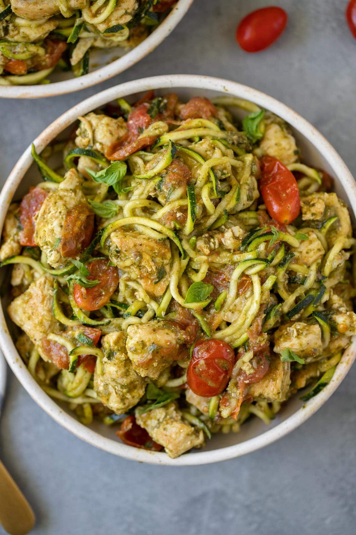 Whole30 Pesto Chicken Zucchini Noodles in a white bowl on a grey background