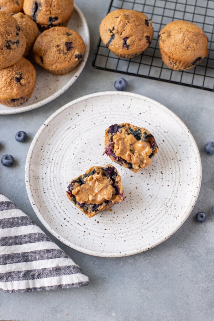 A close up of easy blueberry muffins sliced in half with peanut butter on top