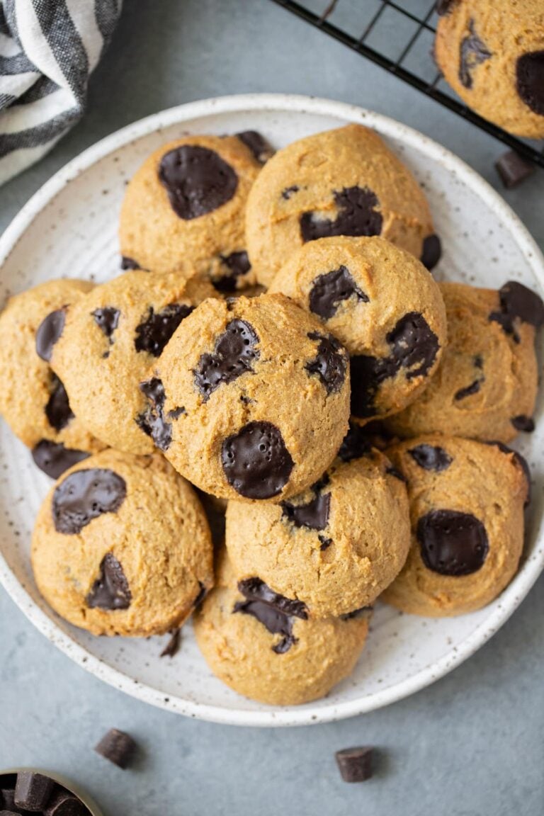 A close up of Healthy Chocolate Chip Cookies on a white plate with a linen and cookie sheet off to the side