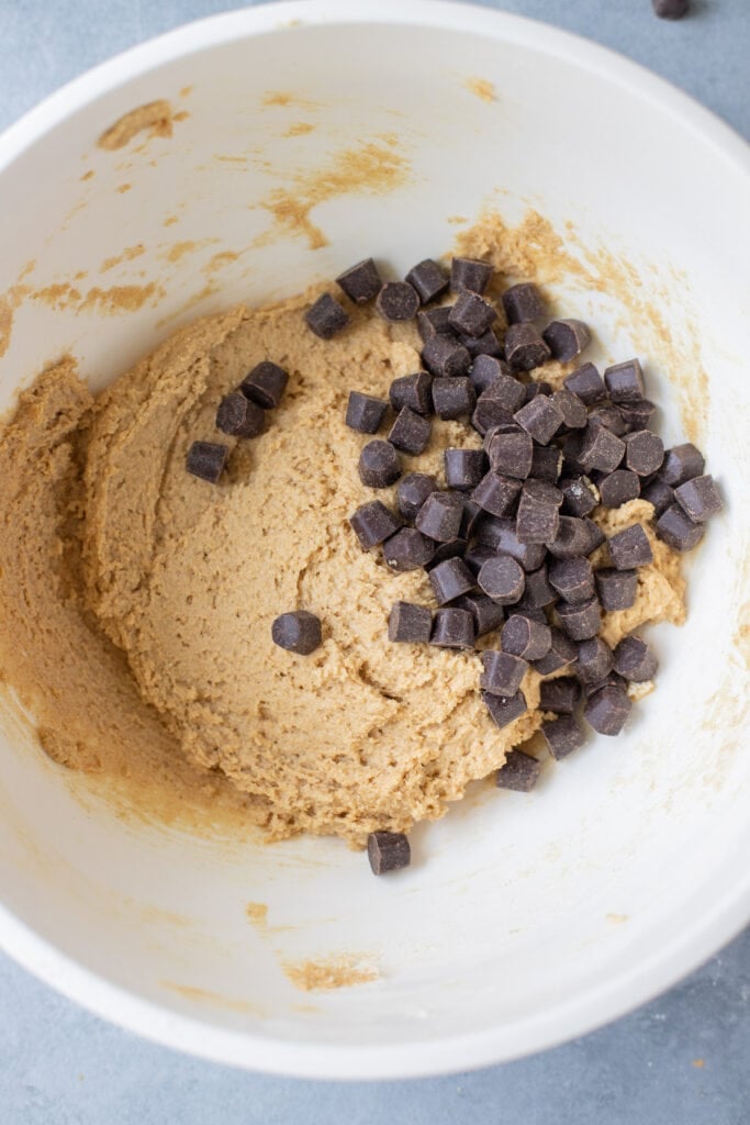 A collage showing step by step how to make whole wheat chocolate chip cookies - mixing together the batter and adding in the chocolate