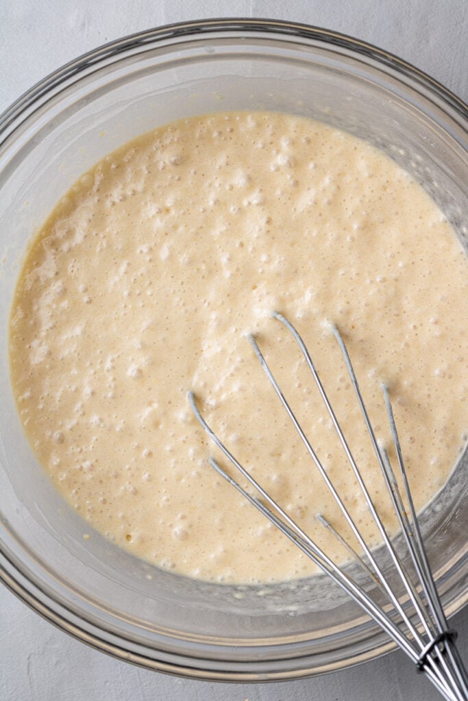 batter for healthy pancakes being mixed together with a whisk in a glass bowl
