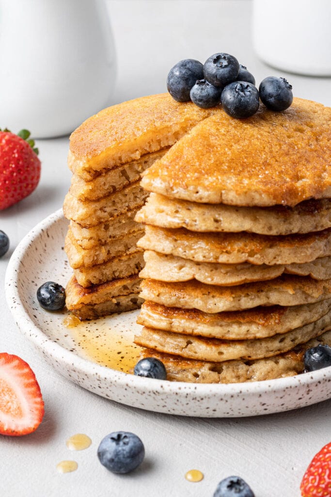 a close up of a stack of fluffy healthy blueberry pancakes with a bite taken out of them