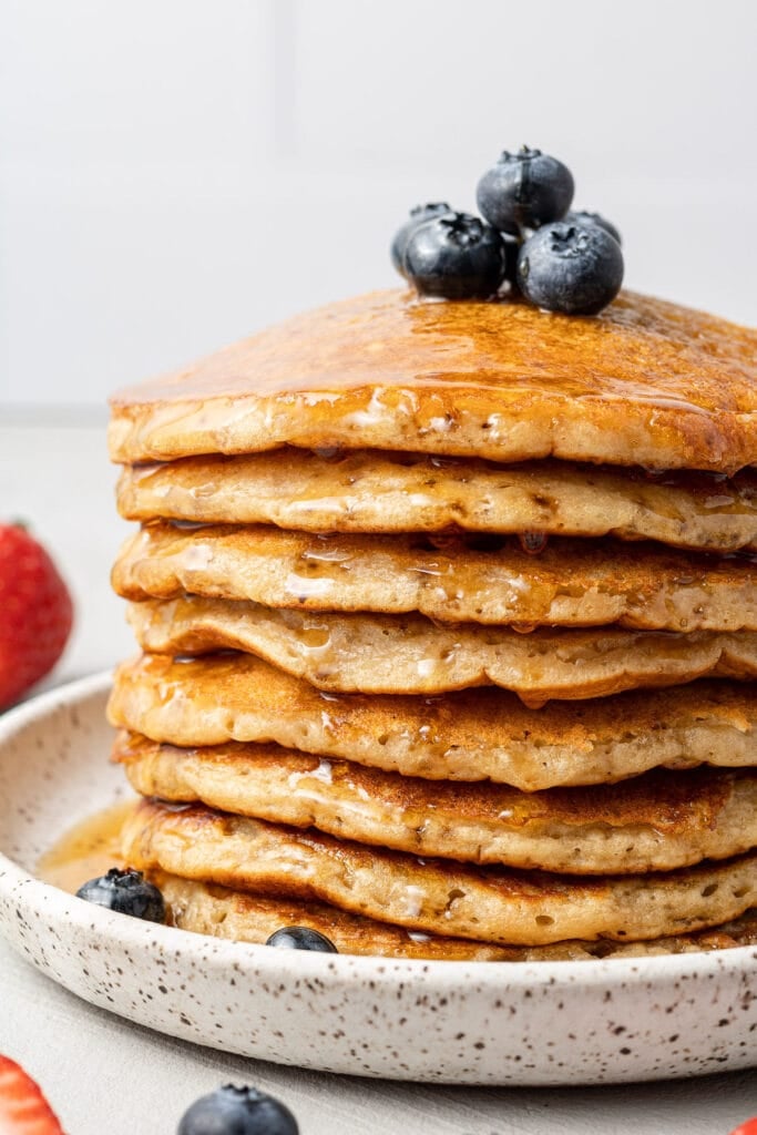 a close up of a stack of fluffy healthy pancakes with blueberries on top