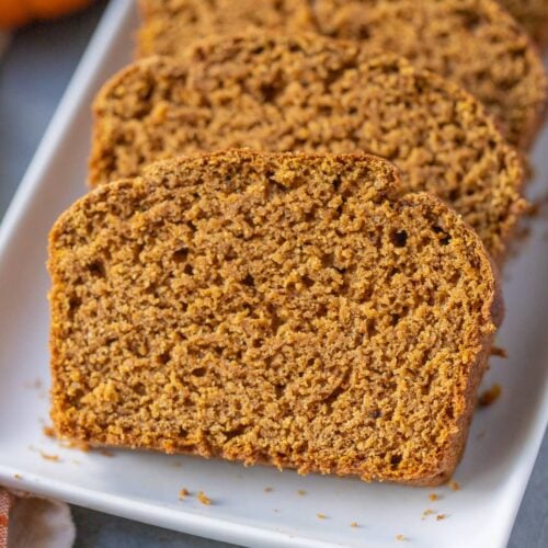 A close up of healthy pumpkin bread on a white dish on a grey background