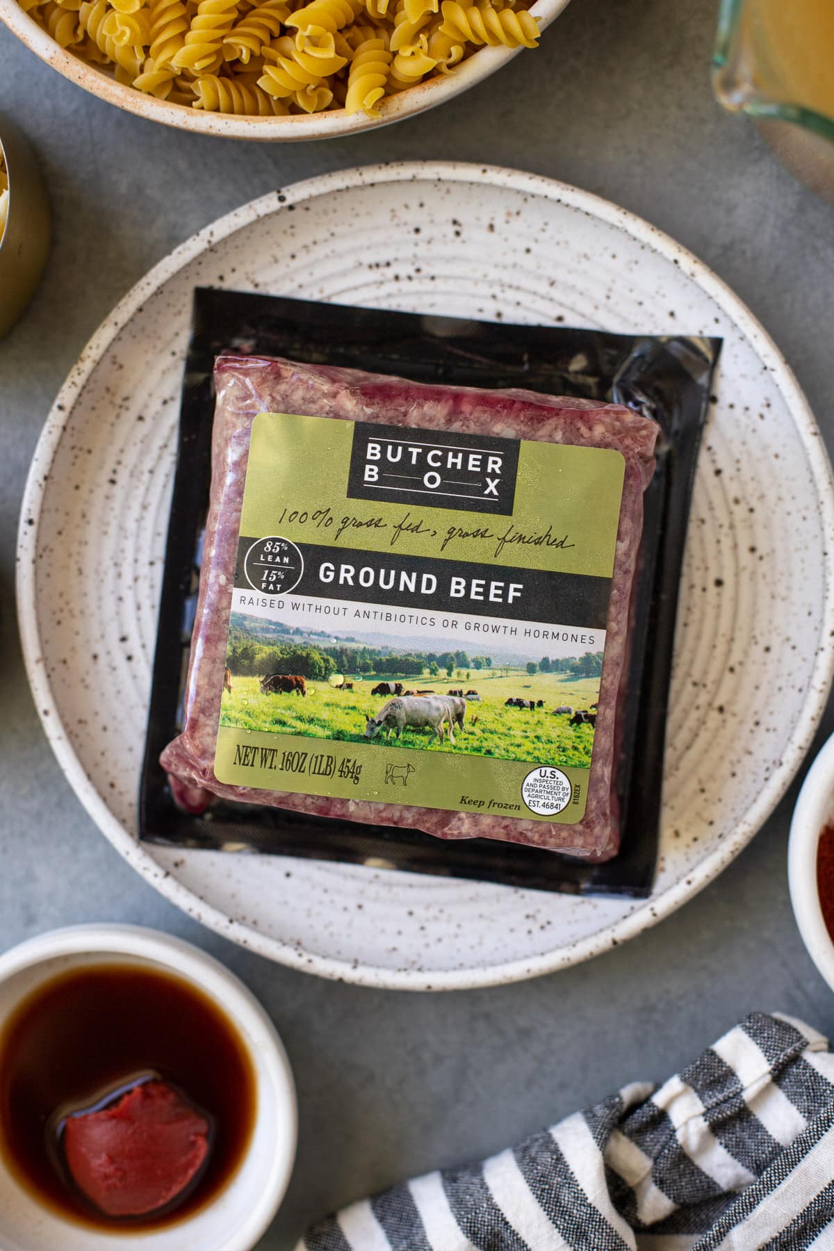 1-pound package of ButcherBox lean ground beef on a white dish, viewed from overhead.