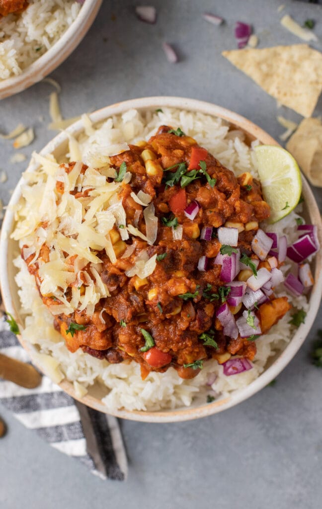 A close up of Vegetarian chili in a white bowl with a striped linen off to the side