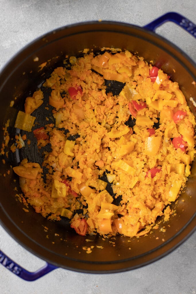 the beginnings of vegetarian chili in a blue dutch oven on a grey background