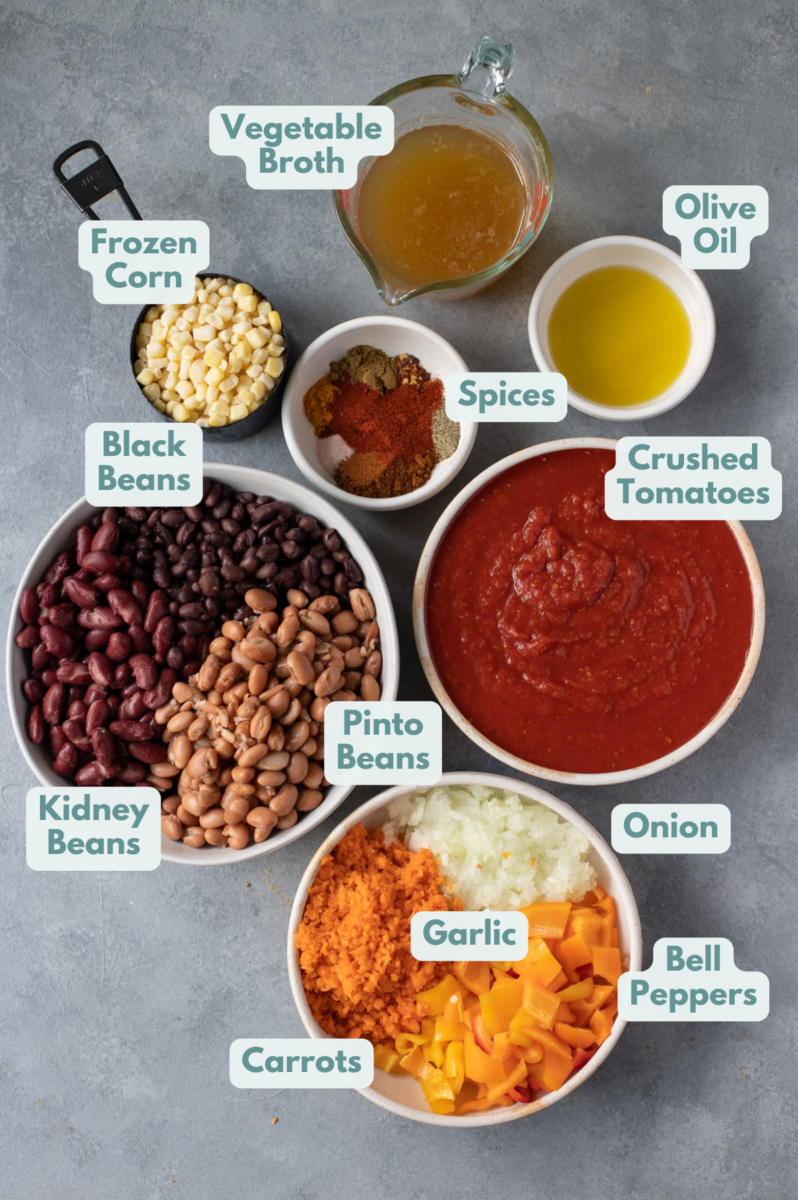 Vegetarian Chili Ingredients in white bowls: olive oil, onion, garlic, peppers, carrots, crushed tomatoes, paprika, red pepper flakes, pepper, chili powder, cumin, salt, ground turmeric, kidney beans, pinto beans, black beans, broth, frozen corn