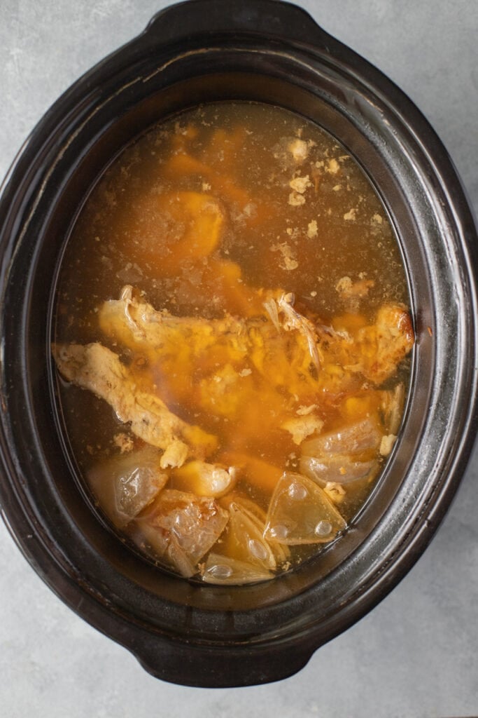 An overhead shot of chicken bone broth in a crockpot base after it has been cooked