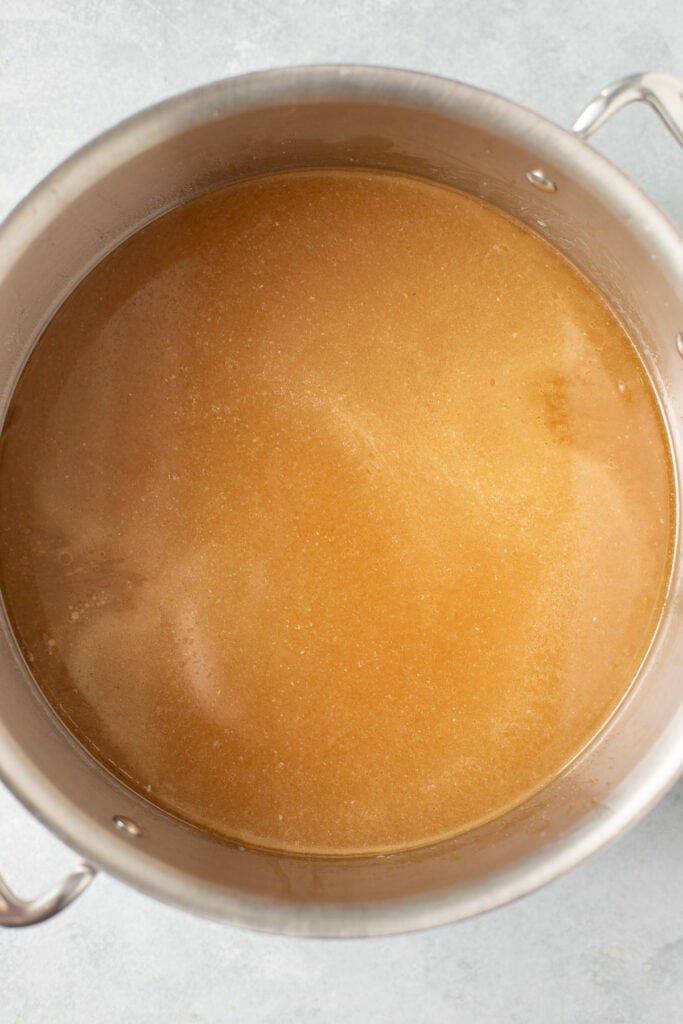 A pot of homemade chicken broth on a grey background