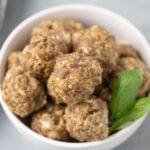A close up of a bowl of homemade meatballs on a grey background