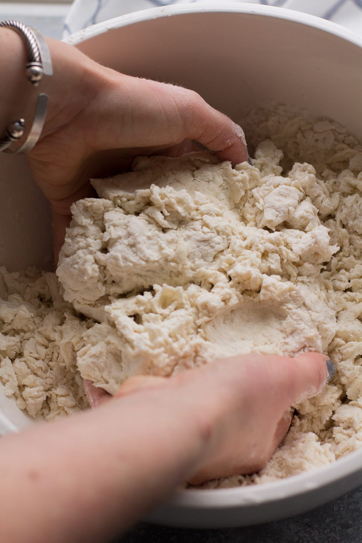 Two hands combining flour, water, and ricotta cheese to make ricotta cavatelli dough.