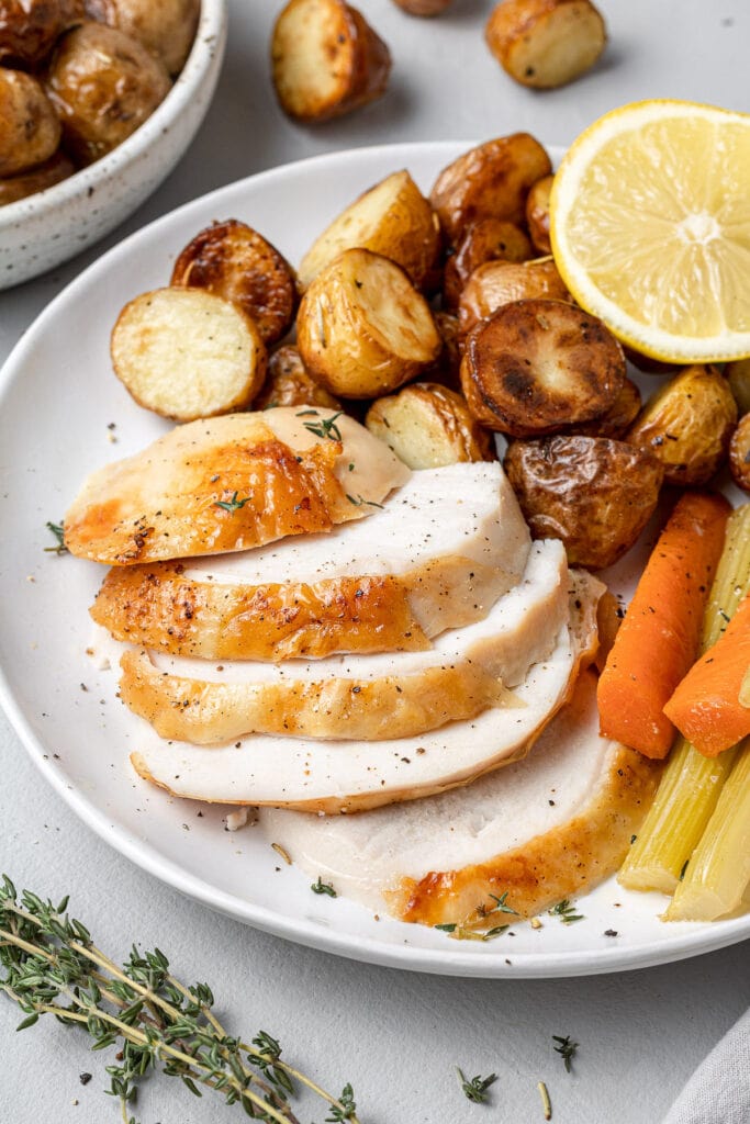 Sliced Oven Roasted Whole Chicken on a plate with potatoes and carrots